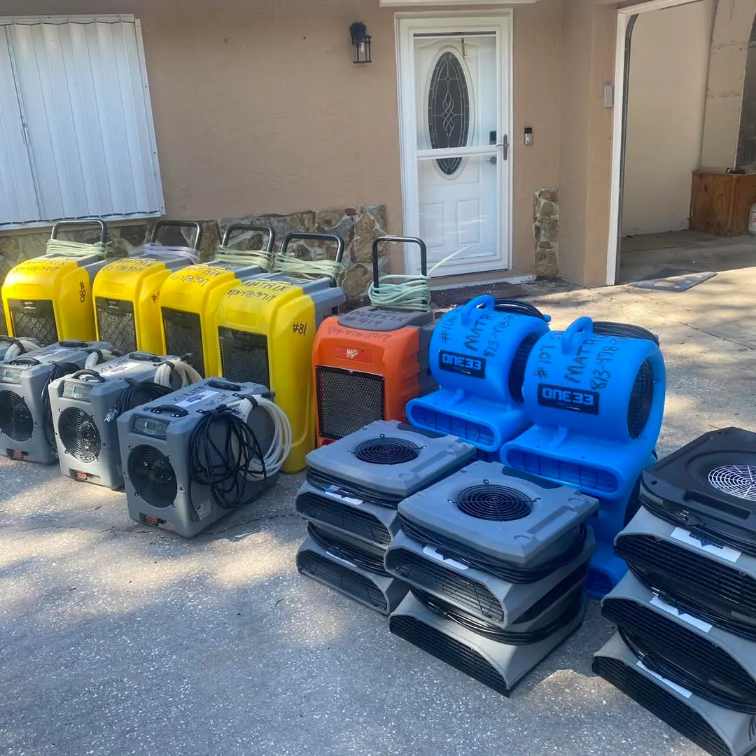 Air movers and dehumidifiers lined up outside a house before drying starts